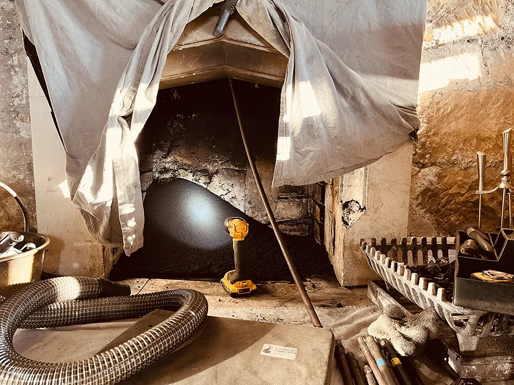 Chimney sweep in progress near Stirling Chimney sweep cleaning an open fire with dust sheets and vacuum equipment near Stirling